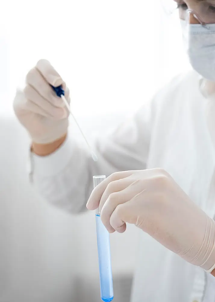 Laboratory technician holding test tube with blue liquid sample