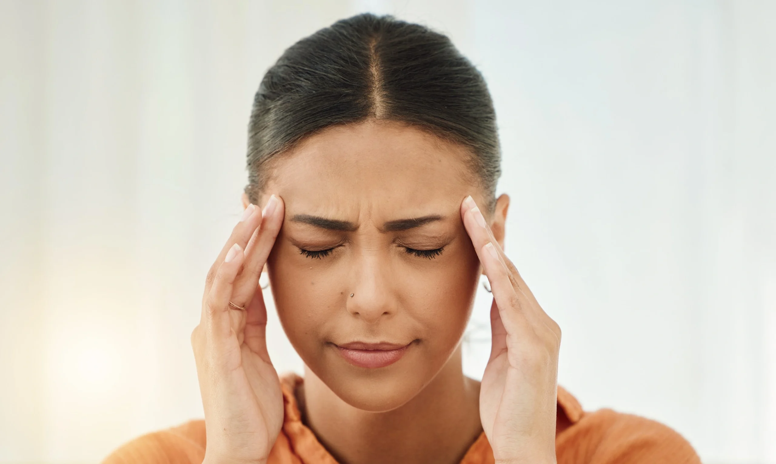Woman experiencing migraine headache holding temples in pain