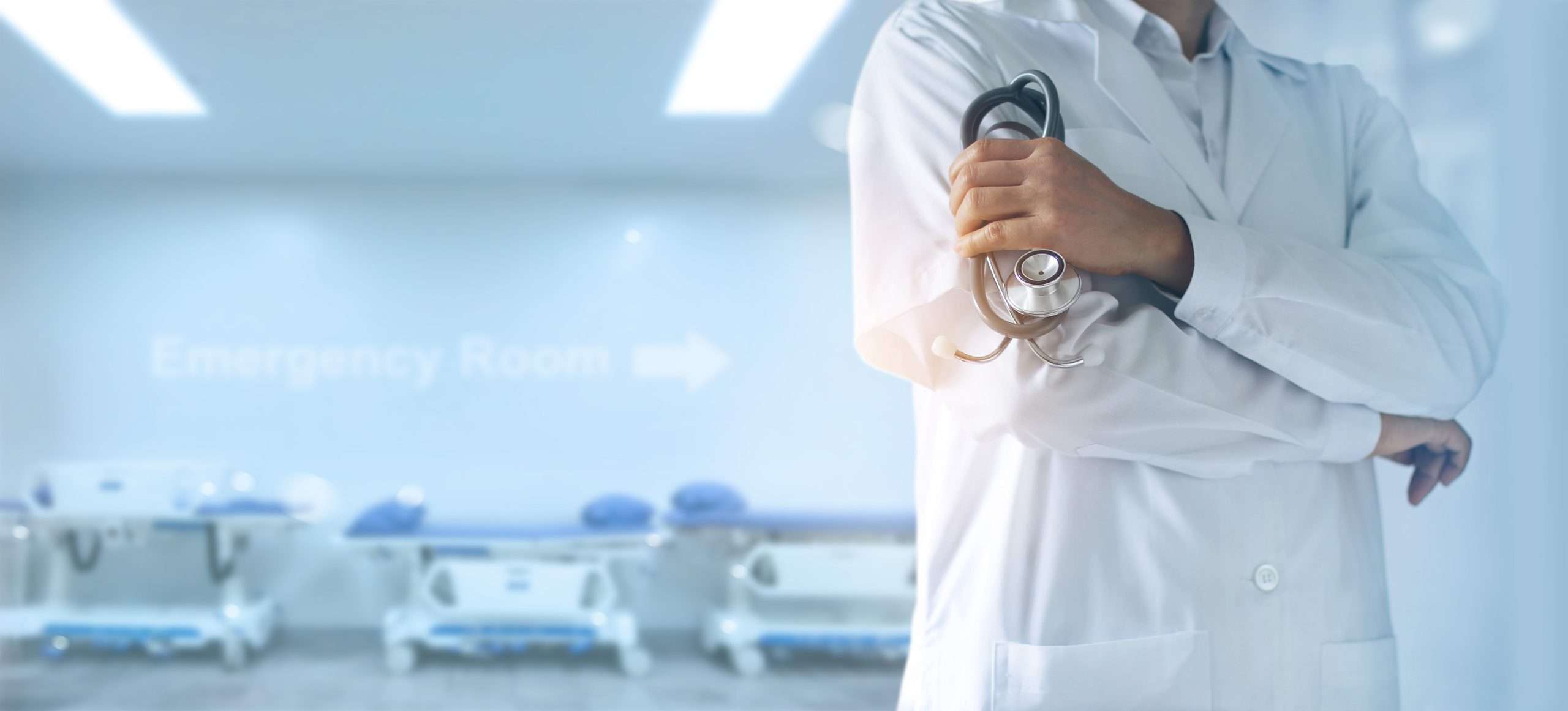 Doctor in white coat holding stethoscope in modern medical facility