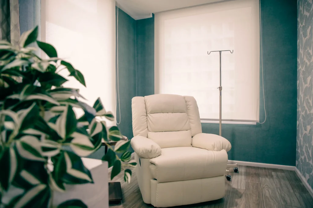 Comfortable cream recliner chair in modern medical treatment room with IV stand