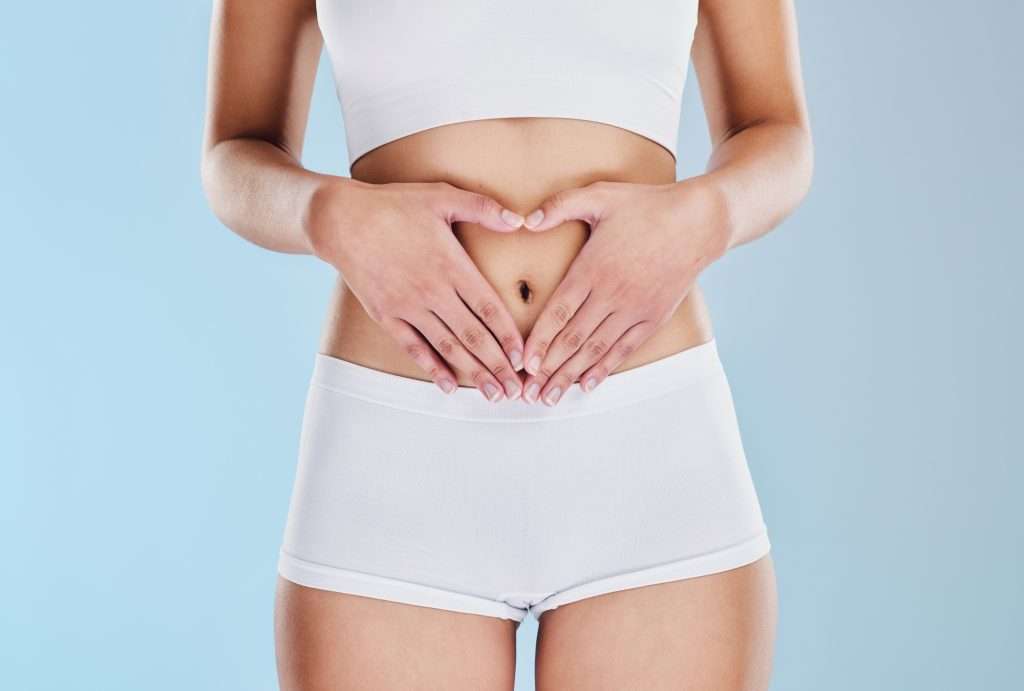Woman holding hands over stomach showing digestive health and wellness