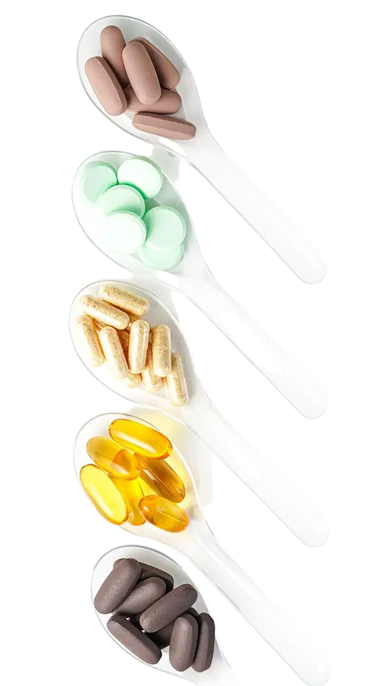 Various vitamin and mineral supplement pills on white spoons