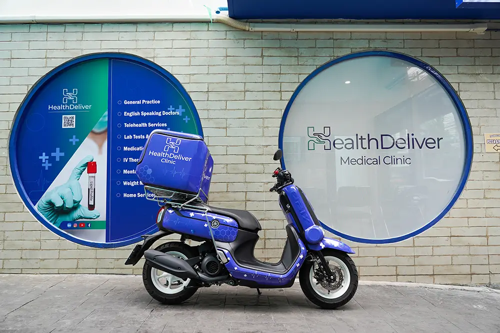 Blue delivery scooter parked in front of HealthDeliver Medical Clinic signage