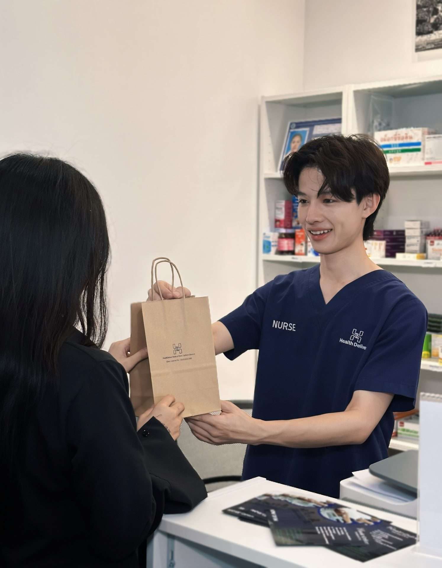 Nurse handing medication bag to patient at pharmacy counter